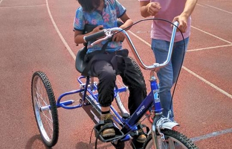 A young boy with autism cycling at the Festival in the Park 2017 in Wythenshawe Park Athletics Track