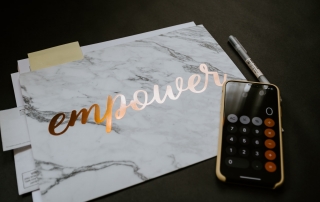 a calculator and a folder containing some documents; the folder has 'empower' printed on it | photo credit: Kelly Sikkema on Unsplash.com
